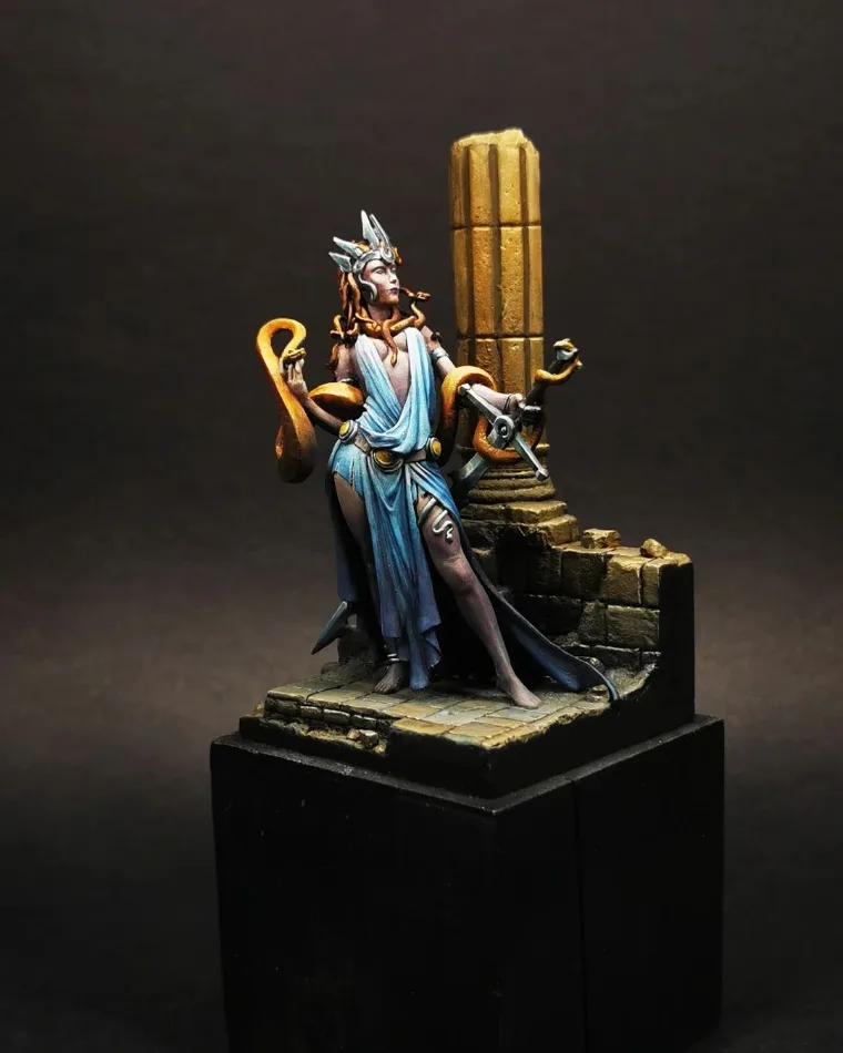 Figurine féminine en robe bleue devant une colonne en ruine, socle décoré